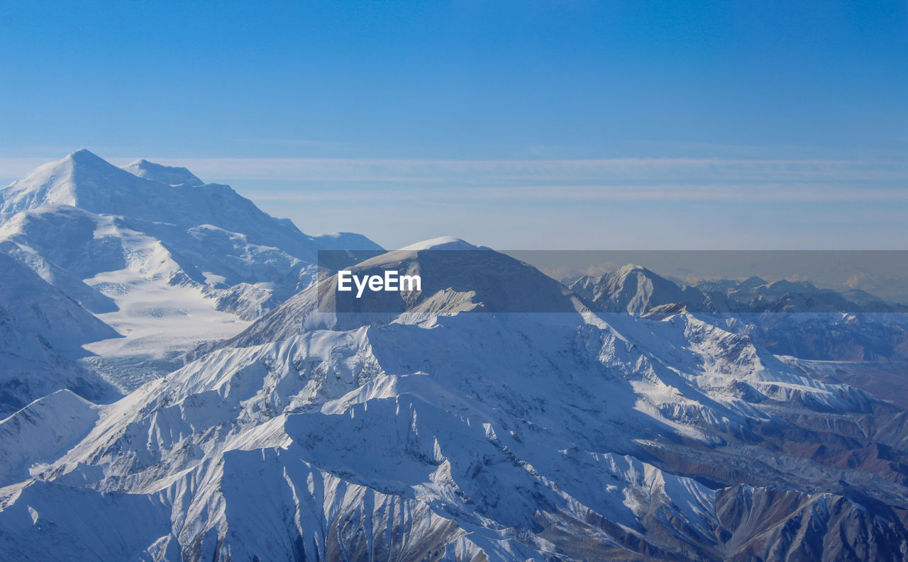 Scenic view of snowcapped mountains against blue sky