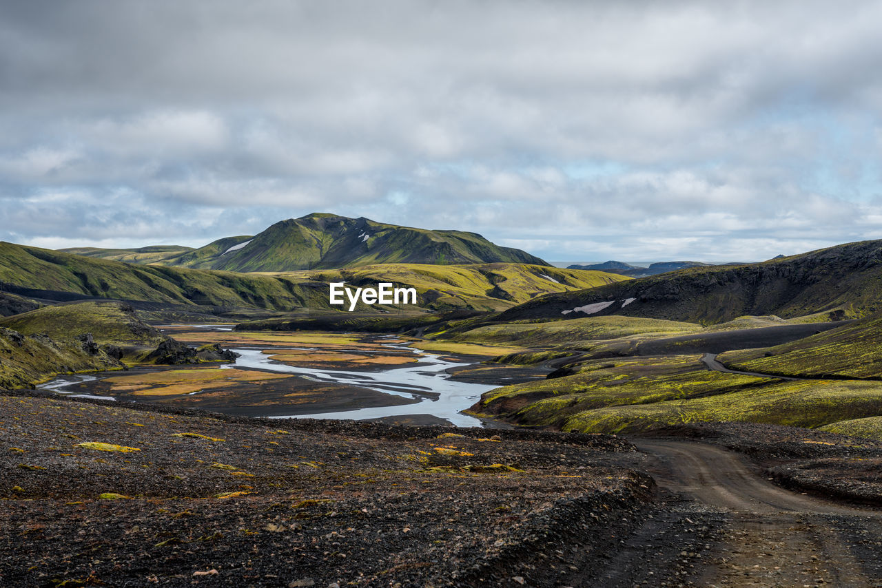 Black dirt road winding through green landscape in iceland