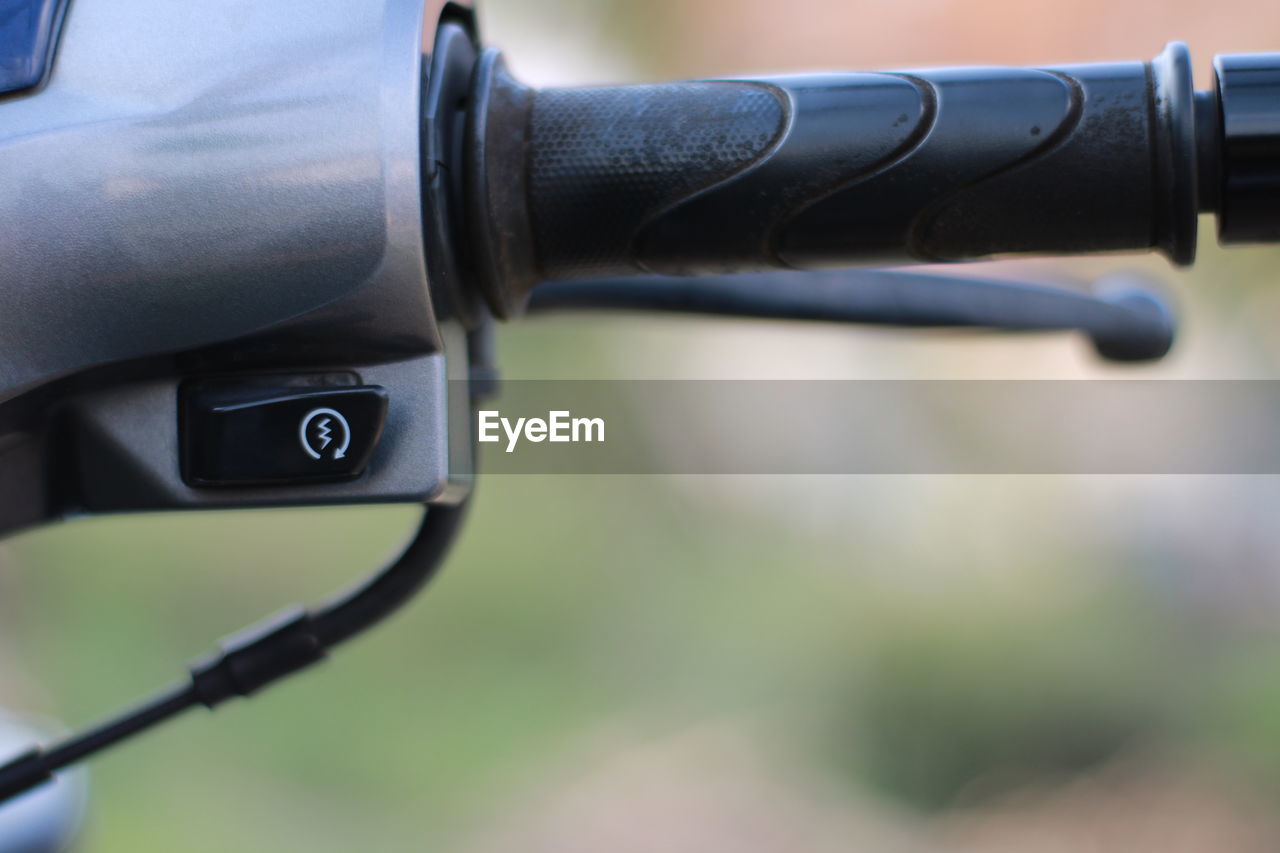 Close-up of power button on handle bar of motorbike.