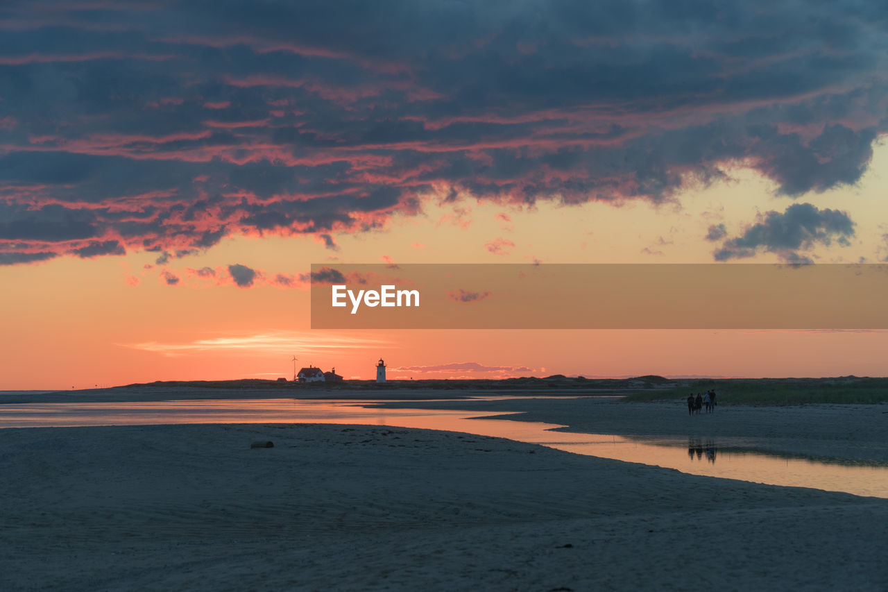 Scenic view of beach against cloudy sky during sunset