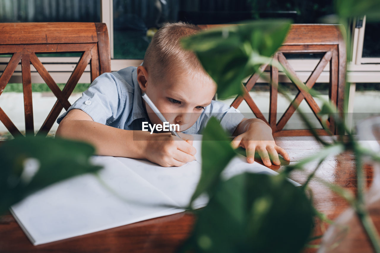 Boy writing in book on table