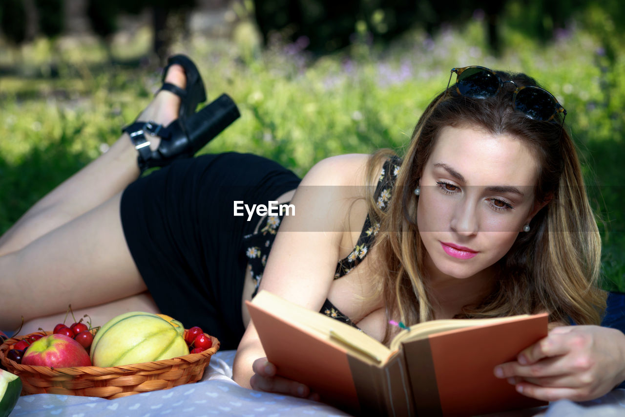 Woman reading book while lying down in park