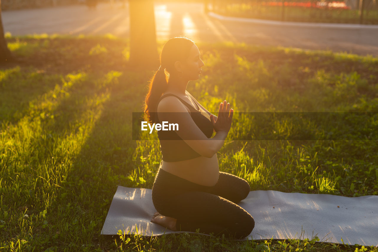 Full length of pregnant woman meditating at park