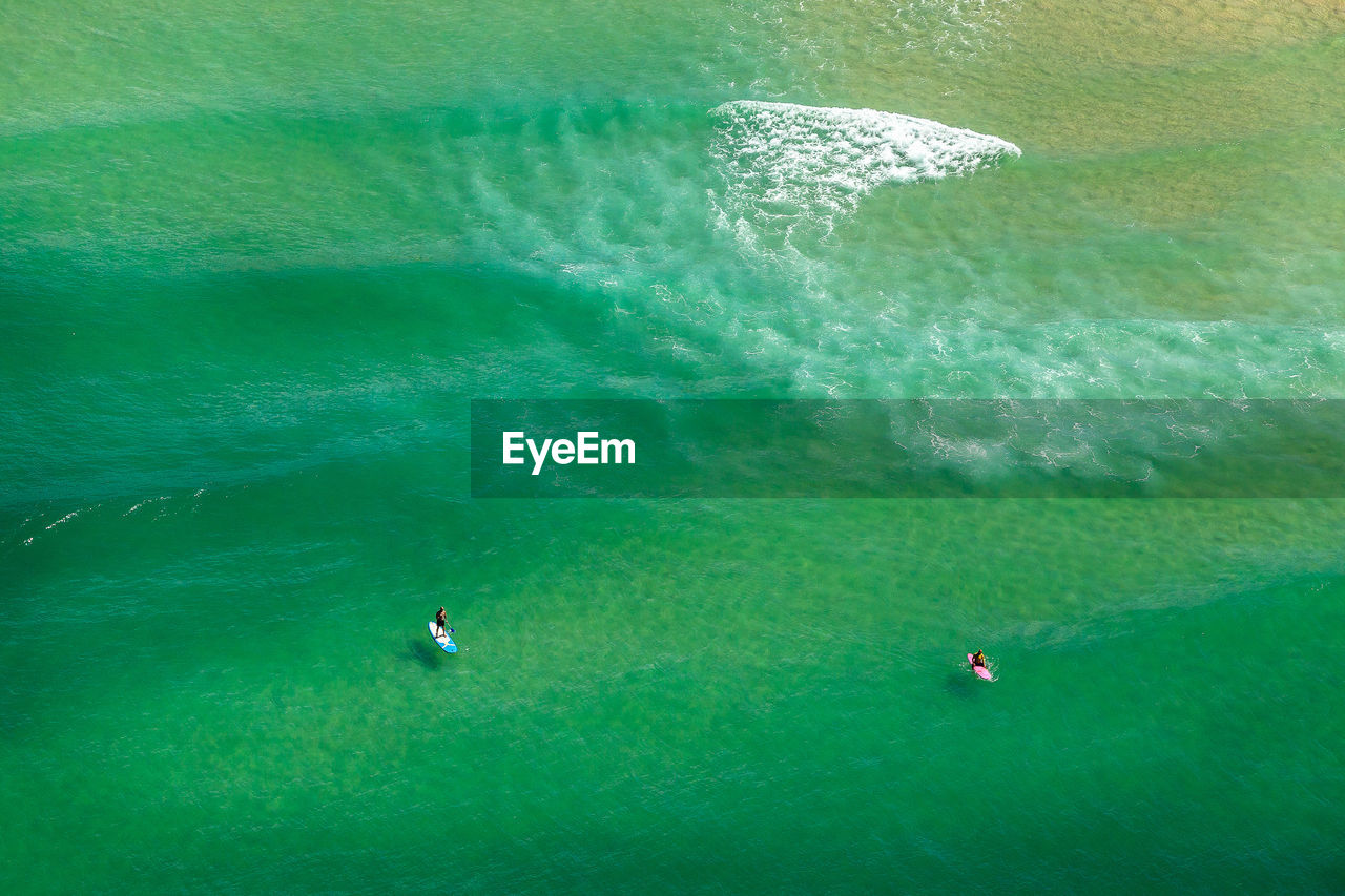 High angle view of friends paddleboarding in sea