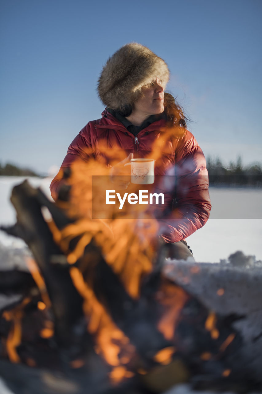 Woman holding mug near campfire