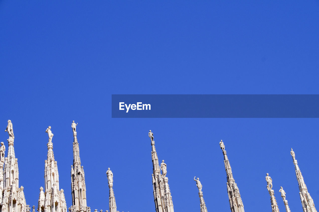 High section of duomo di milano against clear blue sky on sunny day