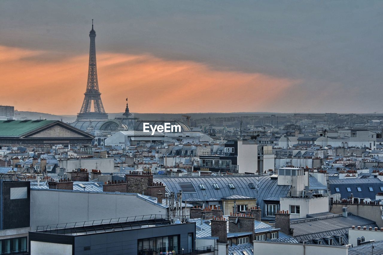 Eiffel tower amidst cityscape during sunset