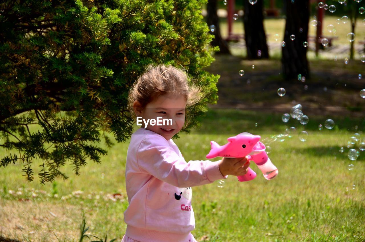 Side view of girl playing with bubble gun