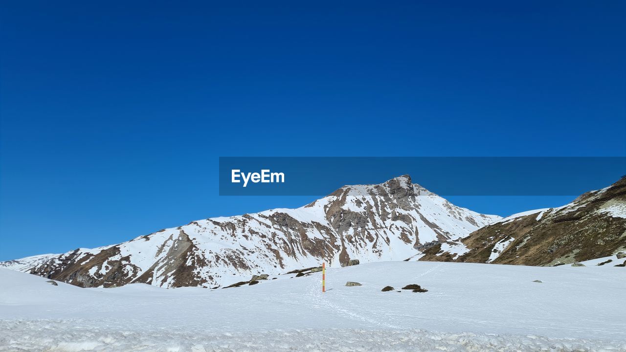 snow, winter, cold temperature, mountain, scenics - nature, sky, environment, mountain range, landscape, beauty in nature, blue, nature, clear sky, snowcapped mountain, copy space, tranquil scene, tranquility, day, travel destinations, no people, travel, sunny, ski mountaineering, ski touring, non-urban scene, ridge, land, frozen, piste, sports, winter sports, outdoors, white, idyllic, mountain peak