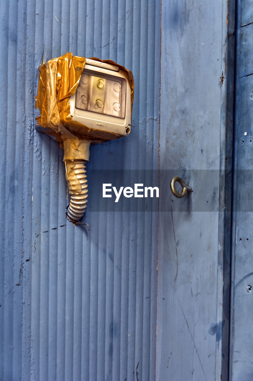 Close-up of electric equipment mounted on purple wall