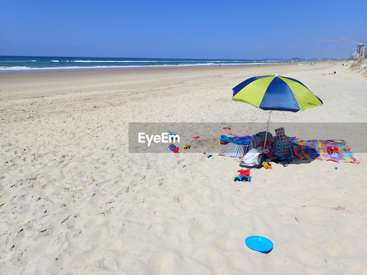 Objects under parasol at beach against clear sky