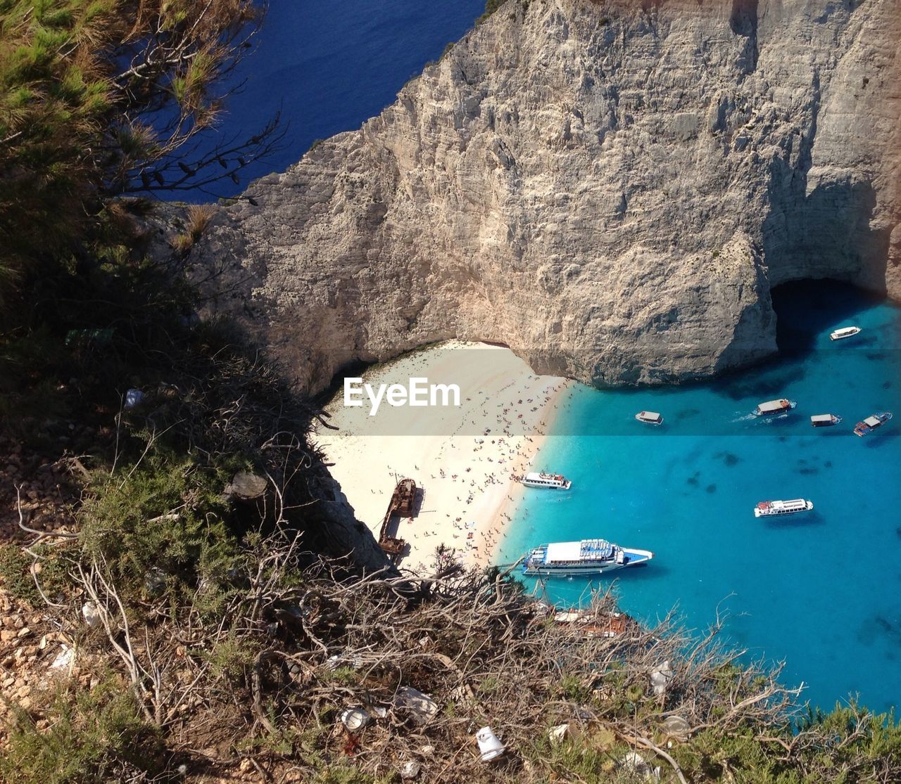 High angle view of boats moored by rock formation in blue sea