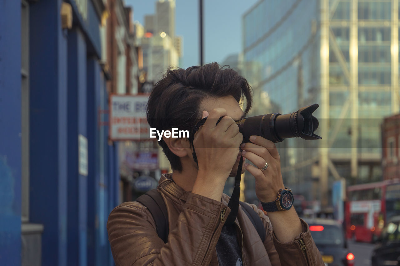 Close-up of man photographing while standing in city