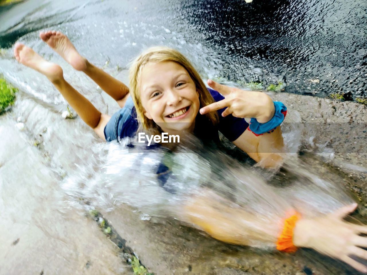 High angle view of water splashing on cheerful girl lying on road