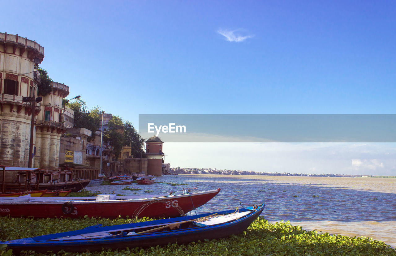 BOATS MOORED AT SEA AGAINST BLUE SKY