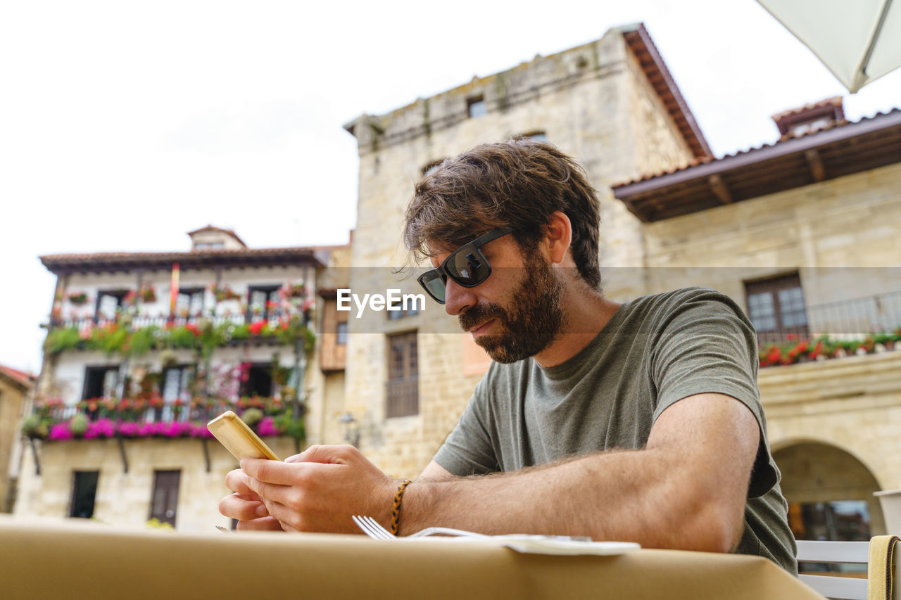 young man using mobile phone while sitting on table