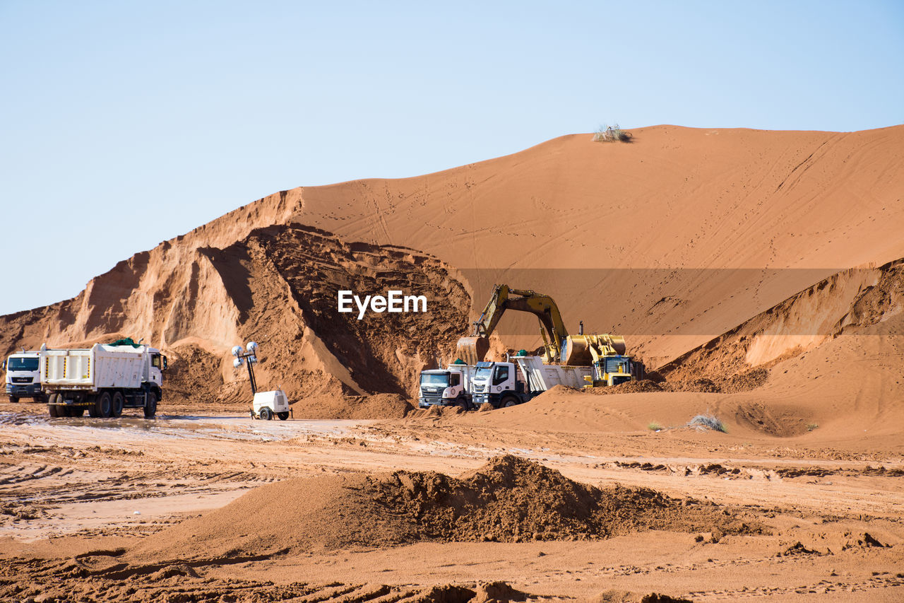 Bulldozer working at desert against sky