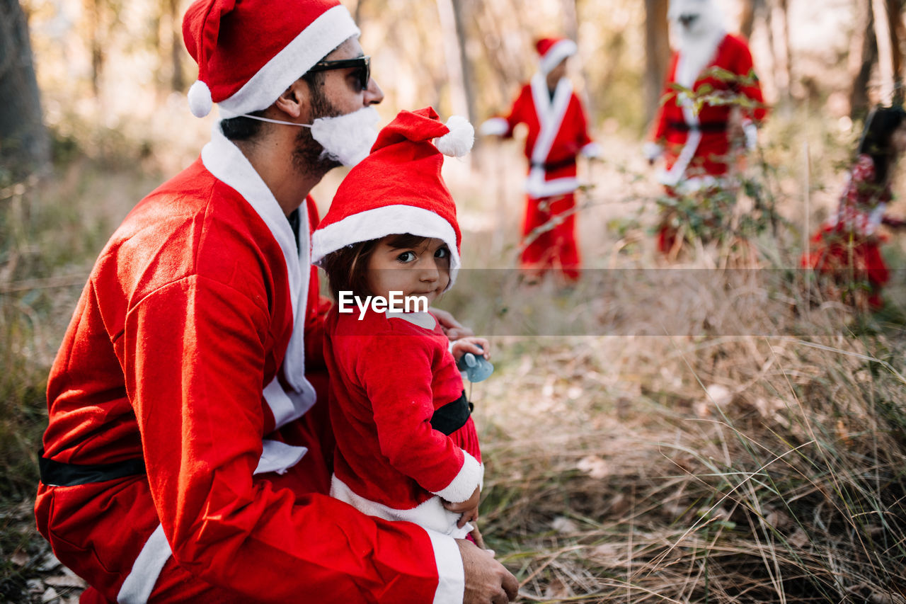 Father and daughter wearing santa costume in forest