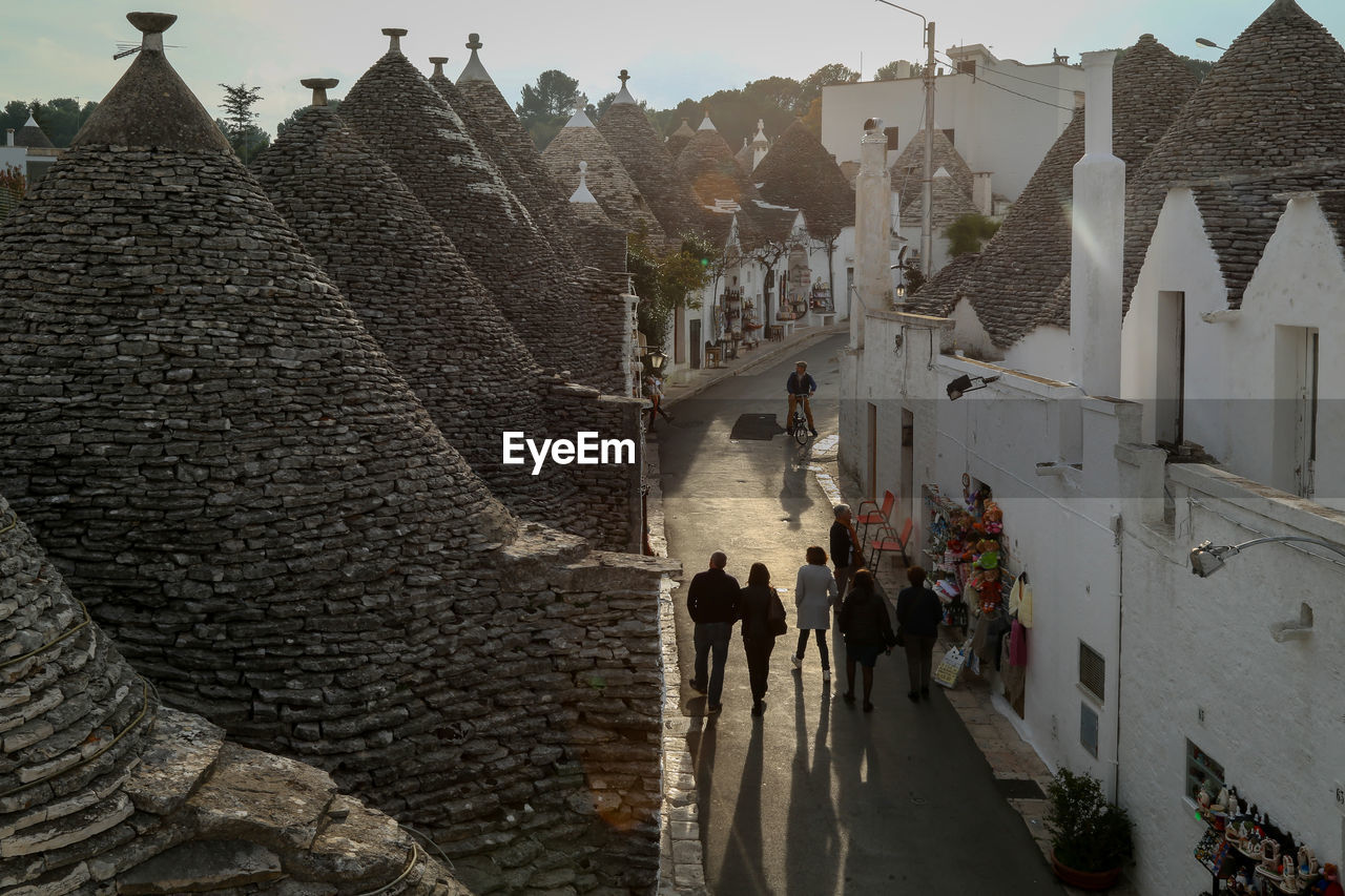 High angle view of people walking on street amidst trullo houses with conical roofs in alberobello