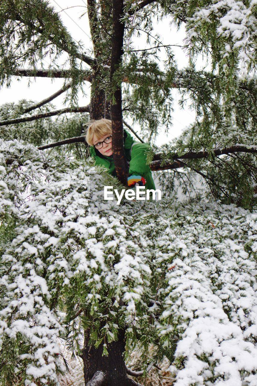 Boy standing by tree during winter