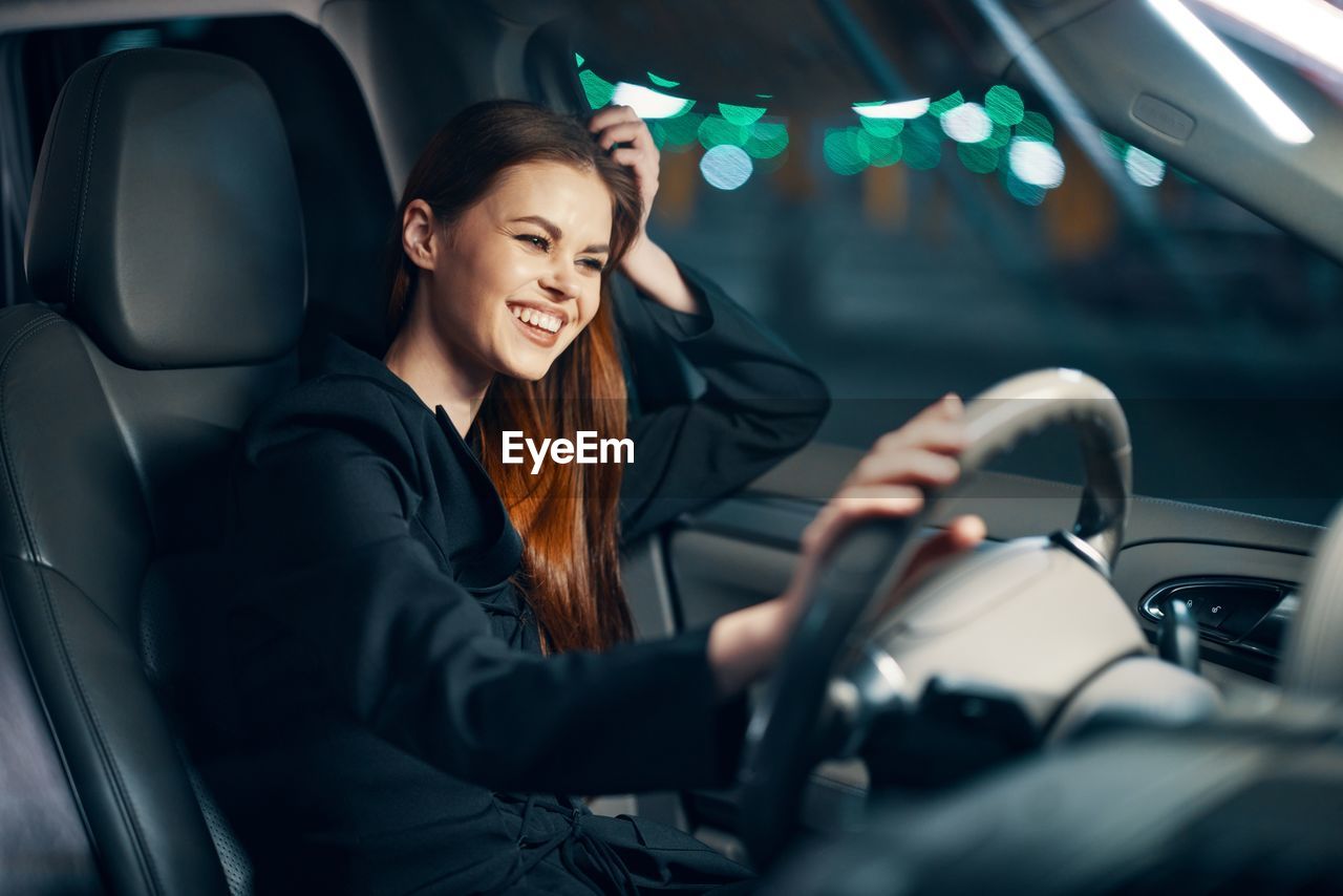 Happy young woman driving car at night