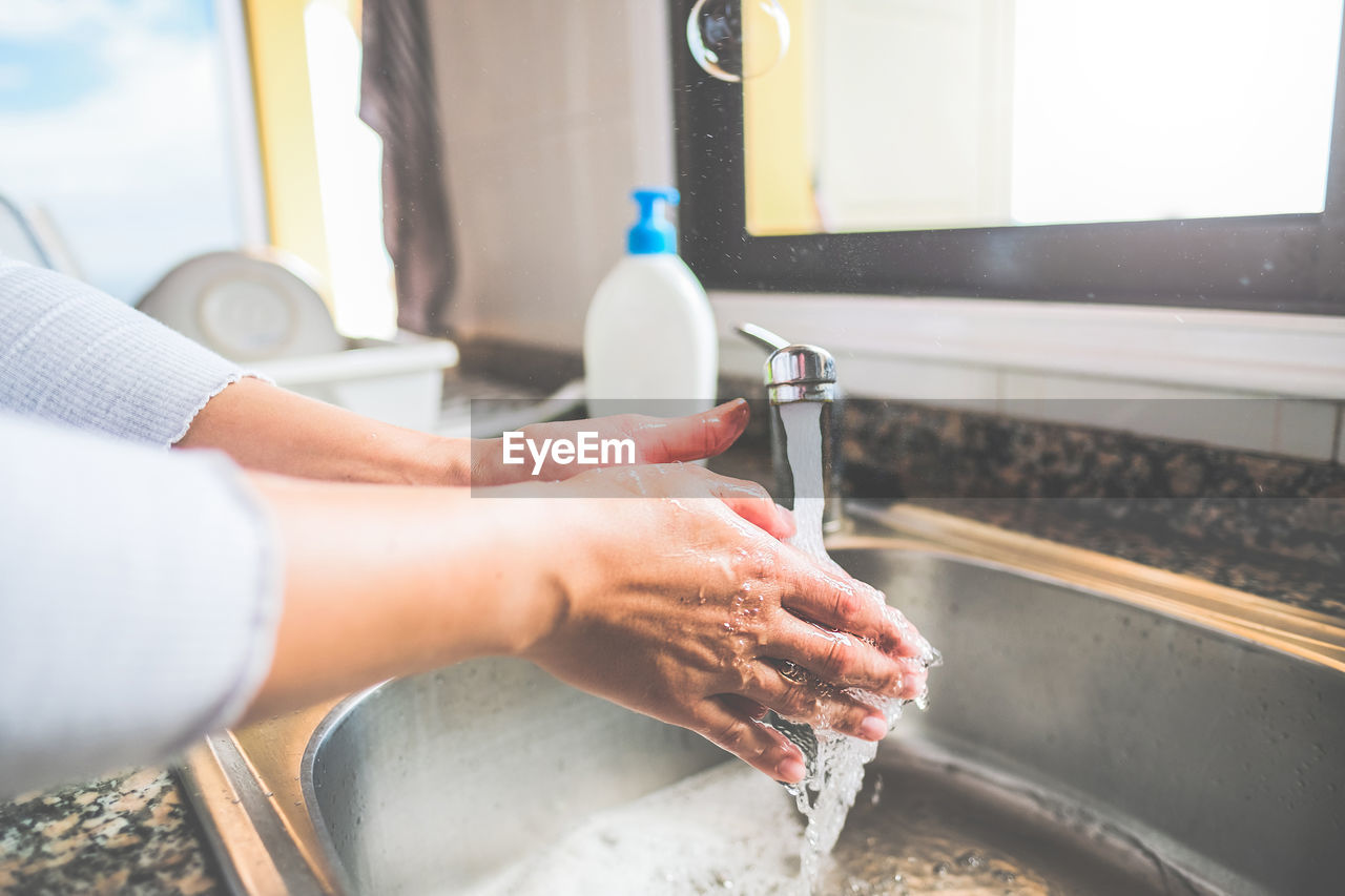 Cropped image of person washing hand in sink