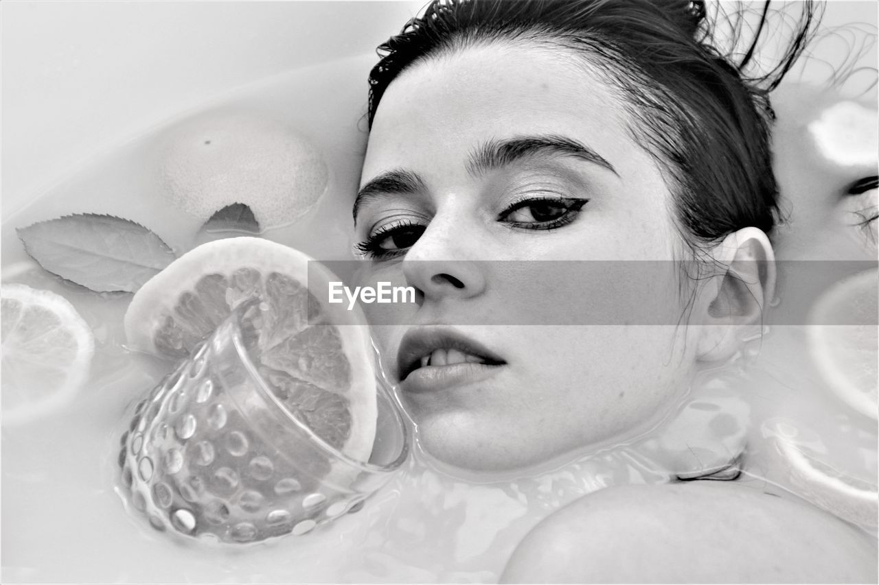 Close-up portrait of woman taking bath with fruits in bathtub