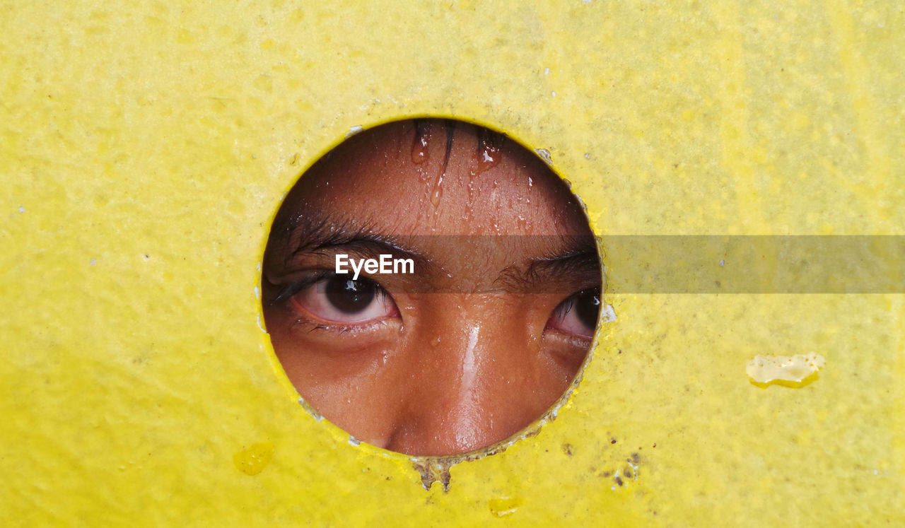 Portrait of wet person peeking through hole