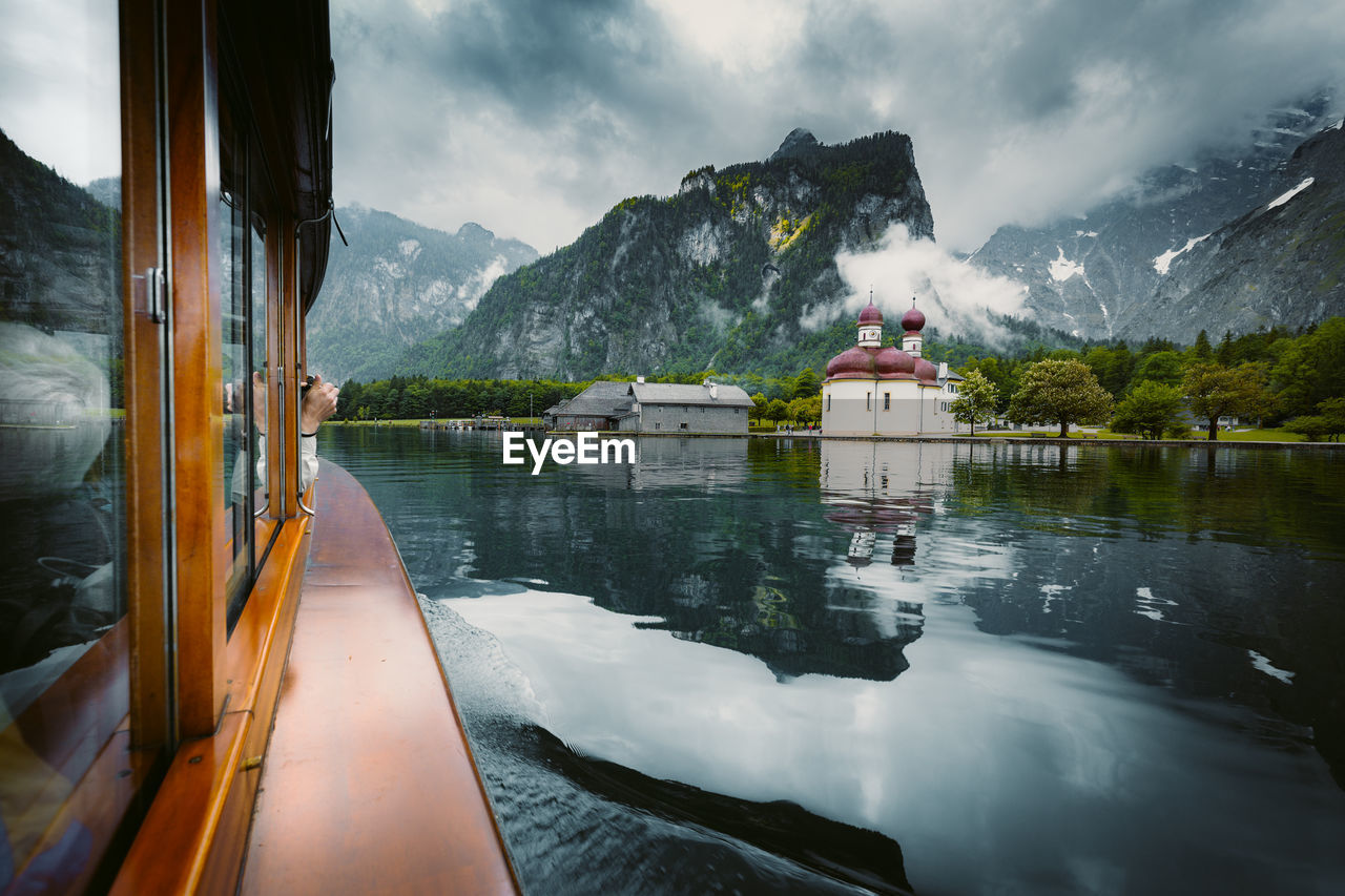 Cropped hand of person in boat at lake against sky