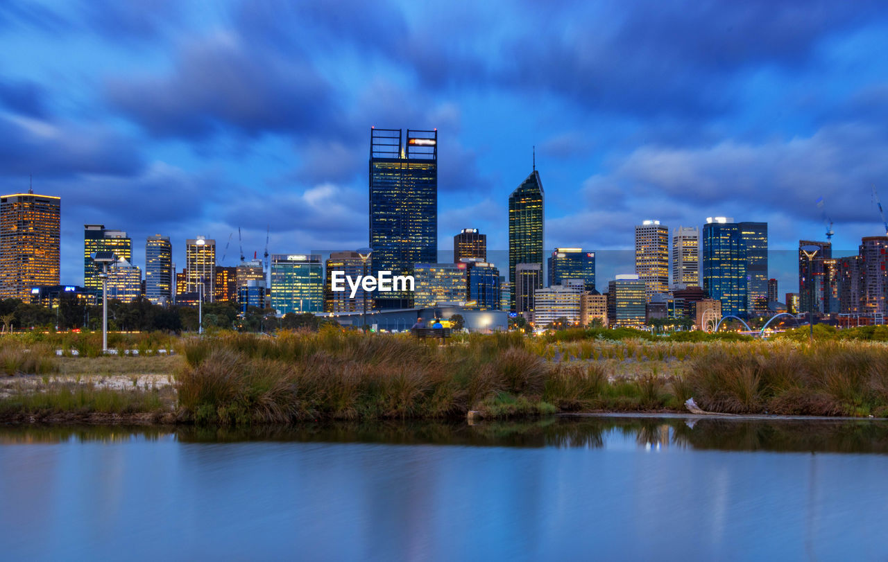 REFLECTION OF BUILDINGS IN LAKE AGAINST SKY