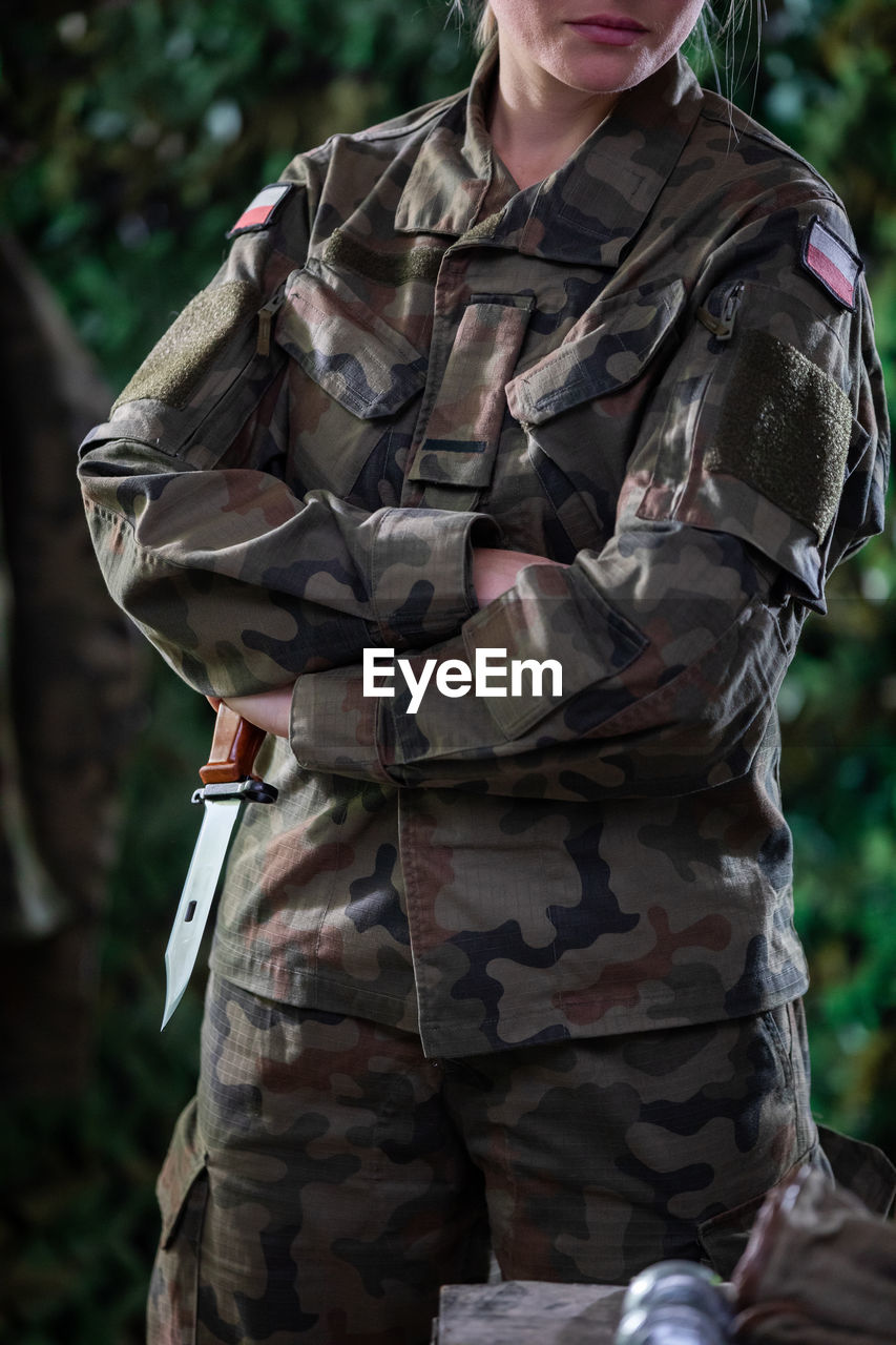 A woman in a moro uniform stands guard with a bayonet in her hand at a temporary commando camp.