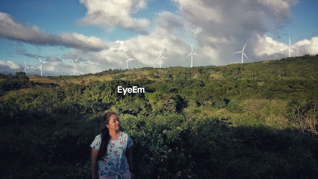 BEAUTIFUL WOMAN STANDING ON FIELD AGAINST SKY