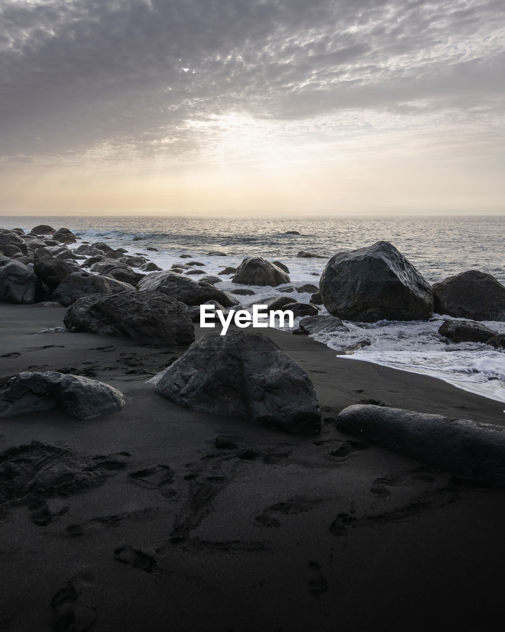 Rocks on beach against sky during sunset