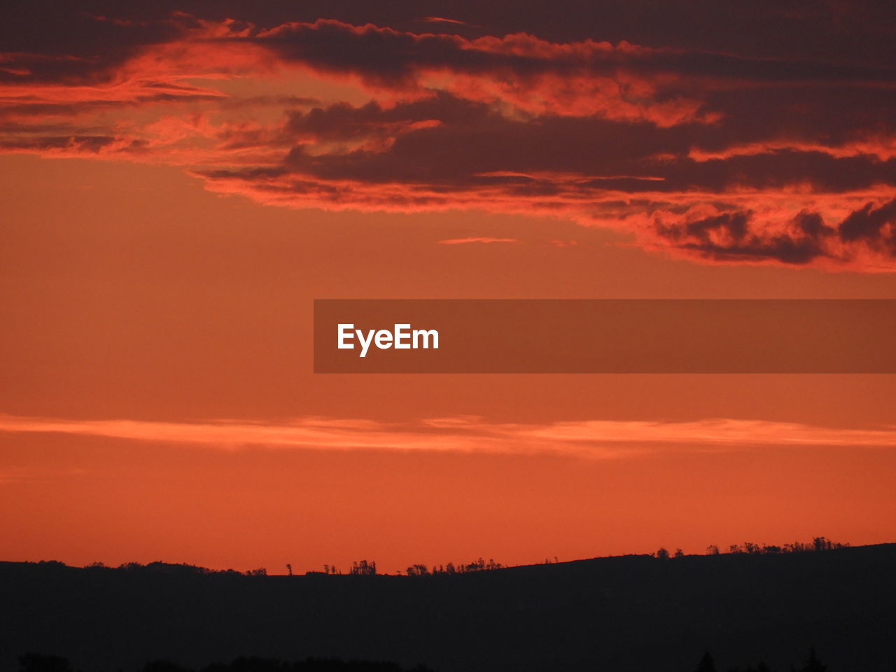 Scenic view of silhouette landscape against dramatic sky during sunset