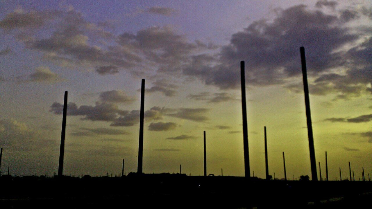 Low angle view of silhouette wooden posts on field at dusk
