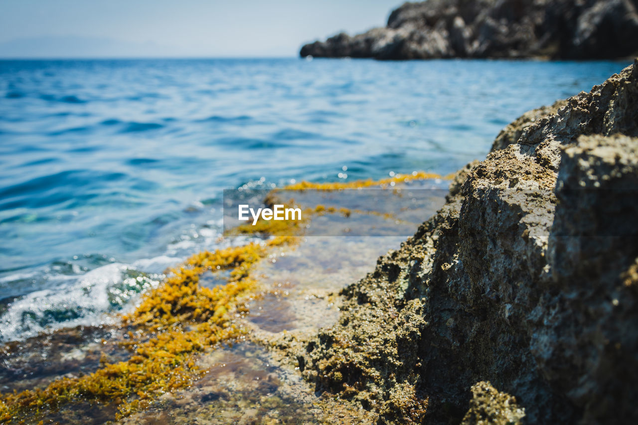 Rock by the sea with the water around in broad daylight