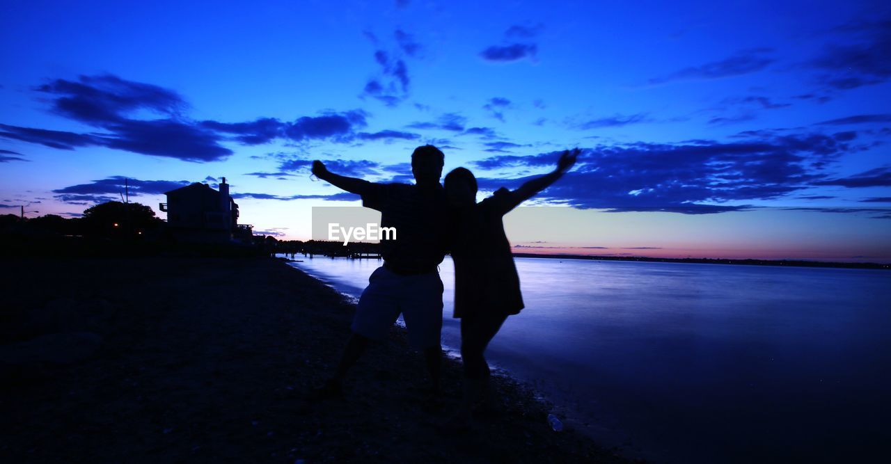 Friends standing against sea during sunset