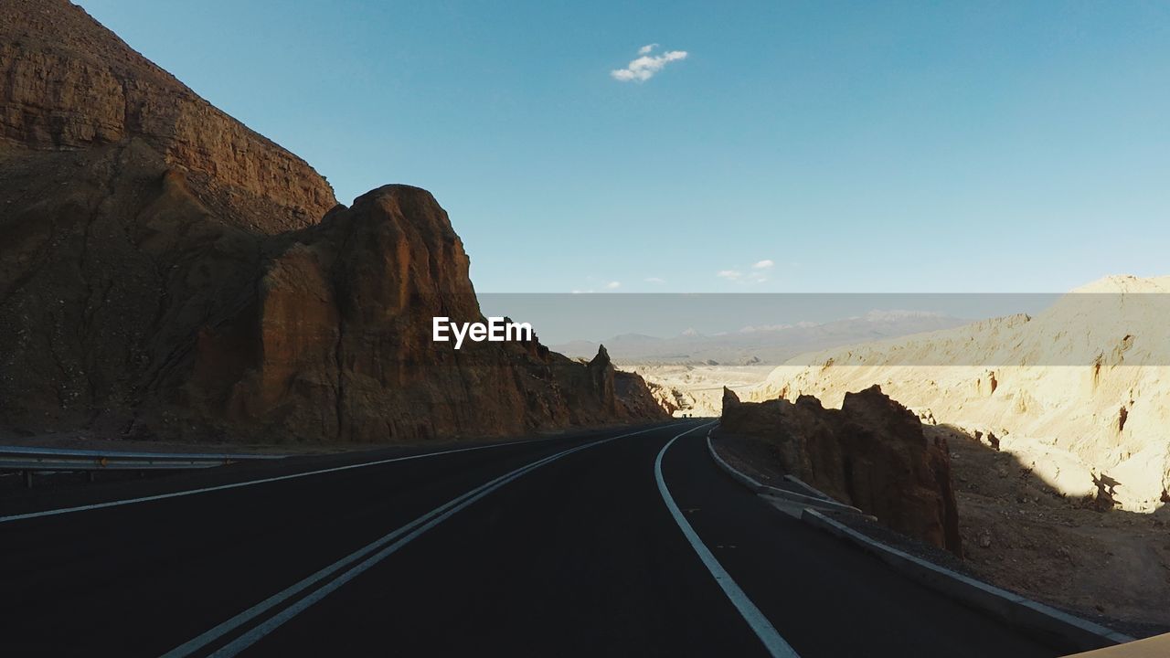 Road leading towards mountains against sky