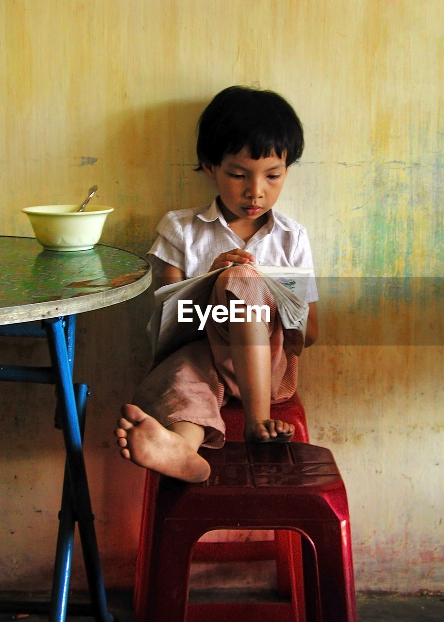 CUTE BOY SITTING ON SEAT AT HOME