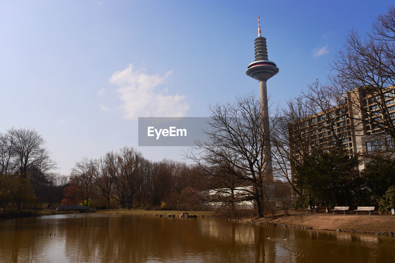 reflection, sky, water, architecture, built structure, tree, tower, nature, travel destinations, building exterior, communications tower, plant, no people, city, tourism, travel, building, lake, outdoors, bare tree, day, technology, evening, communication, cloud