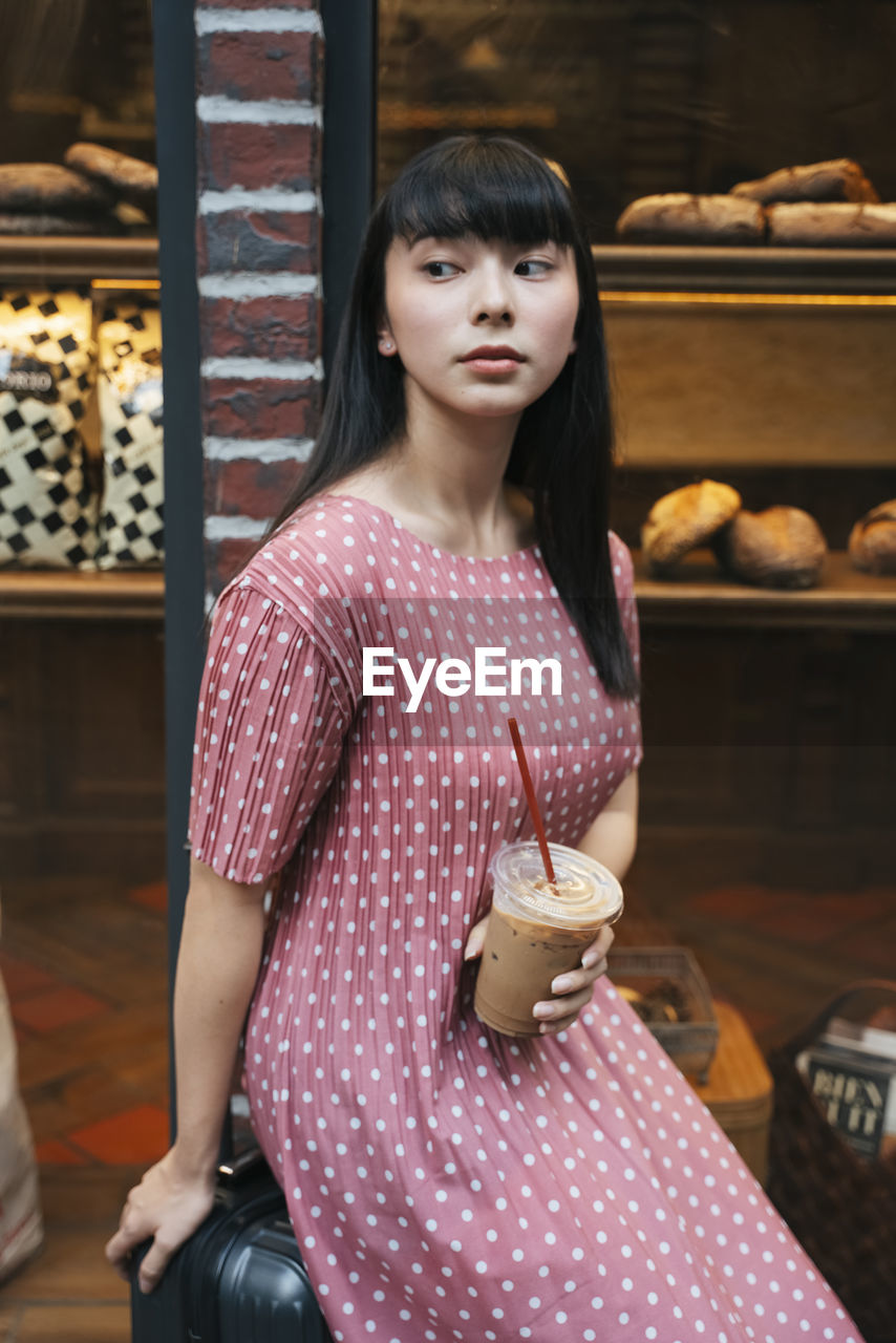 Young woman holding cold coffee outdoors