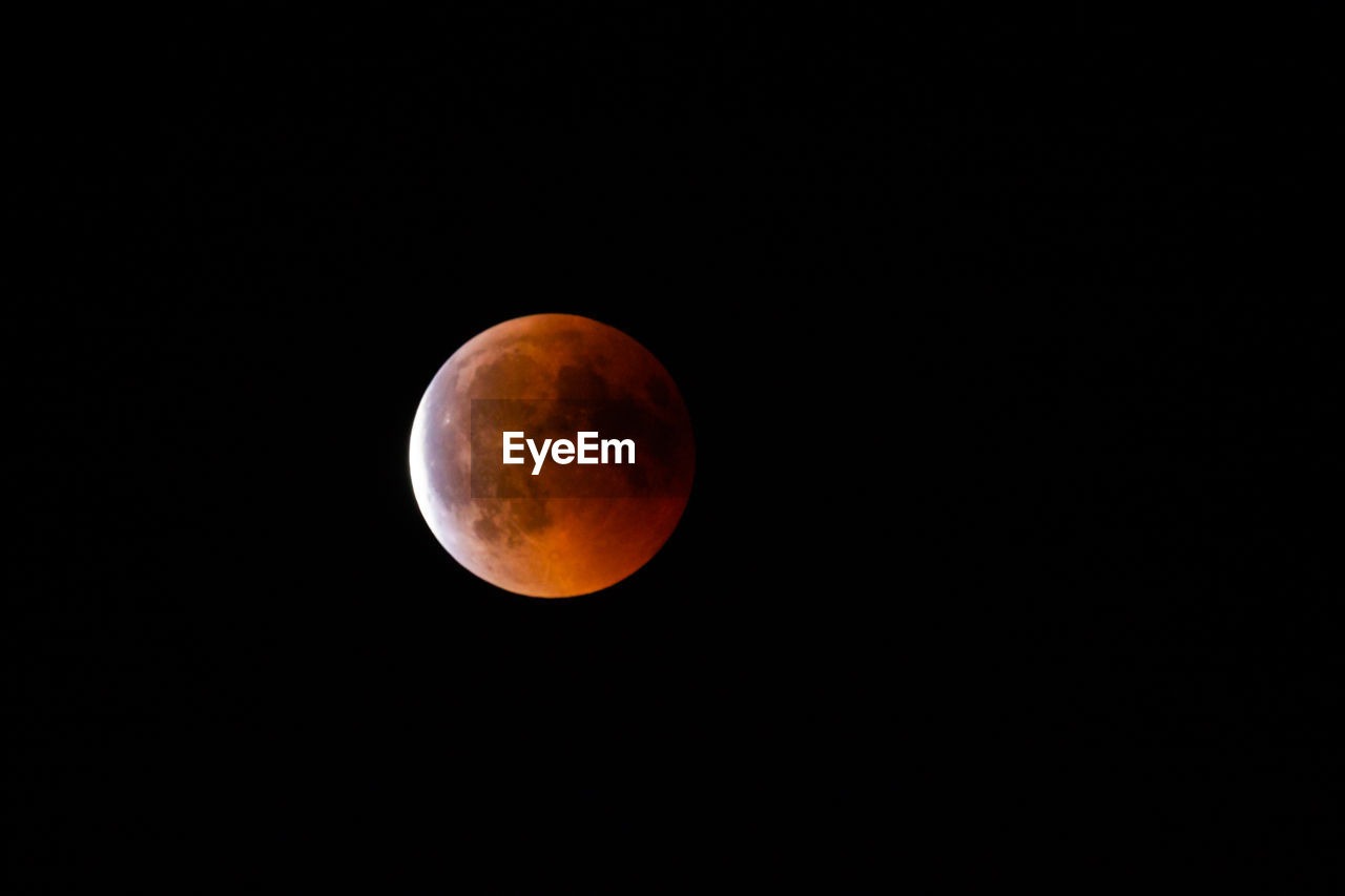 Low angle view of lunar eclipse against clear sky at night