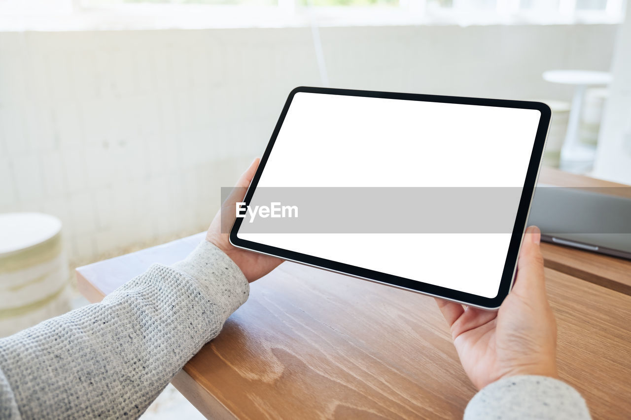 technology, wireless technology, communication, computer, digital tablet, indoors, internet, table, computer network, business, adult, portability, laptop, furniture, tablet computer, screen, hand, home interior, one person, copy space, portable information device, writing, lifestyles, smartphone, computer monitor, desk, relaxation, using computer, holding, touch screen, computer equipment, working, mobile phone, convenience, wood, domestic room, office, device screen