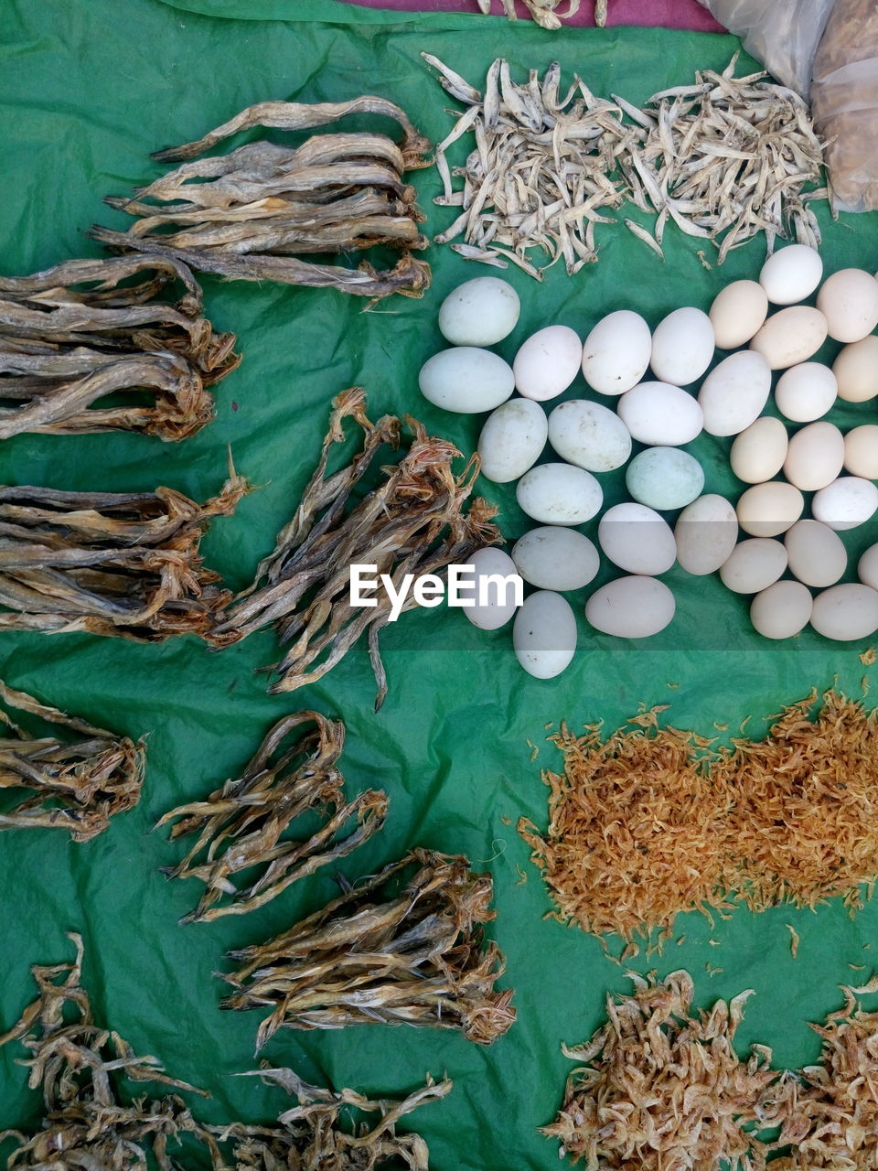 High angle view of dried fish and eggs on plastic at market for sale