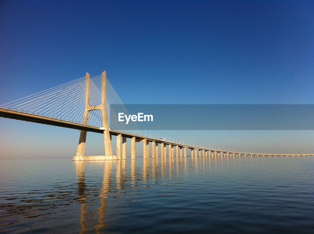 Bridge over calm sea against clear sky