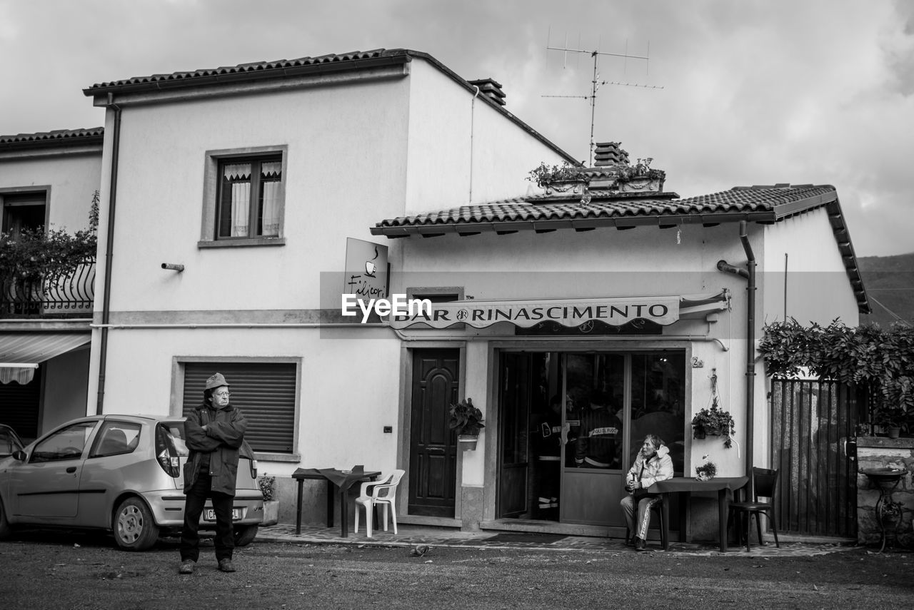 PEOPLE OUTSIDE HOUSE AGAINST BUILDINGS