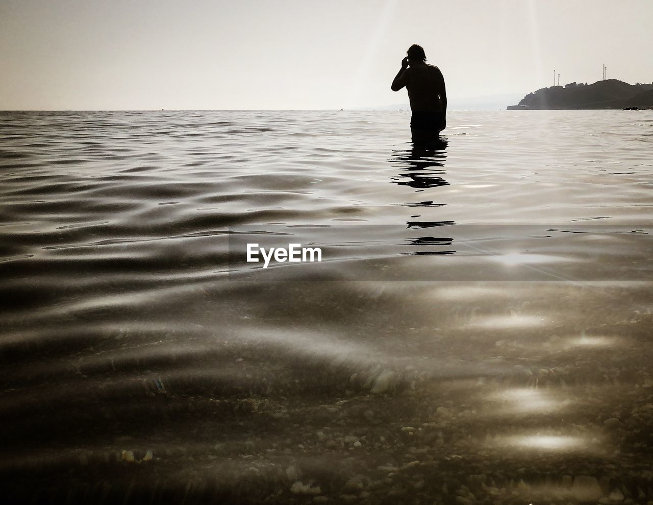 Silhouette man standing in sea against sky