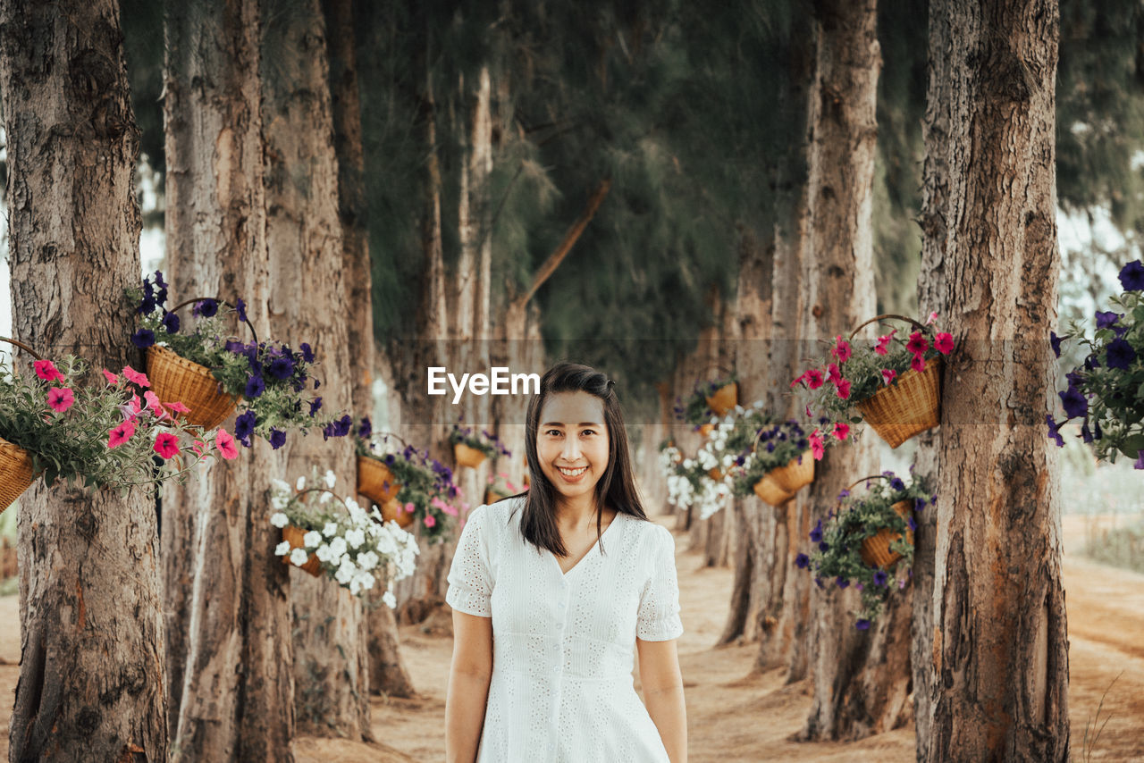 Portrait of smiling woman standing by trees