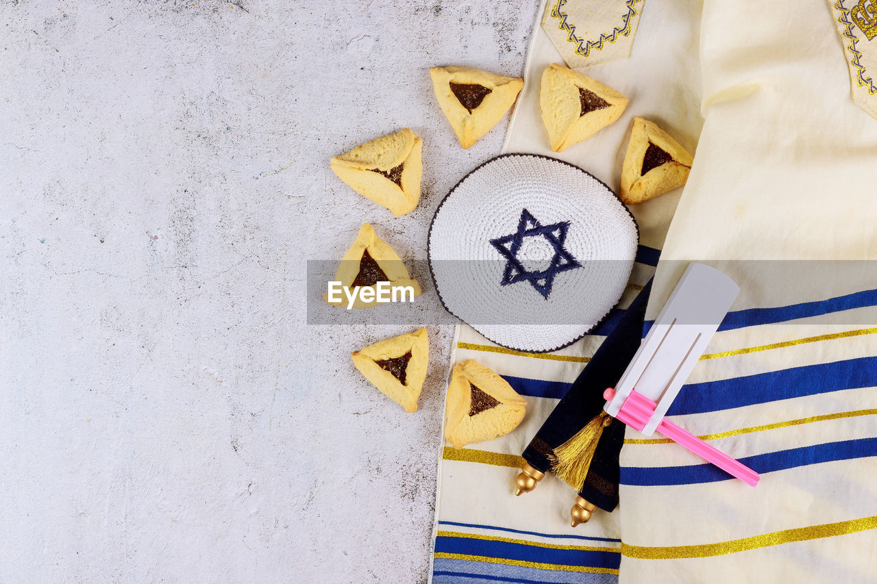 Jewish carnival purim celebration on hamantaschen cookies, noisemaker and mask with parchment