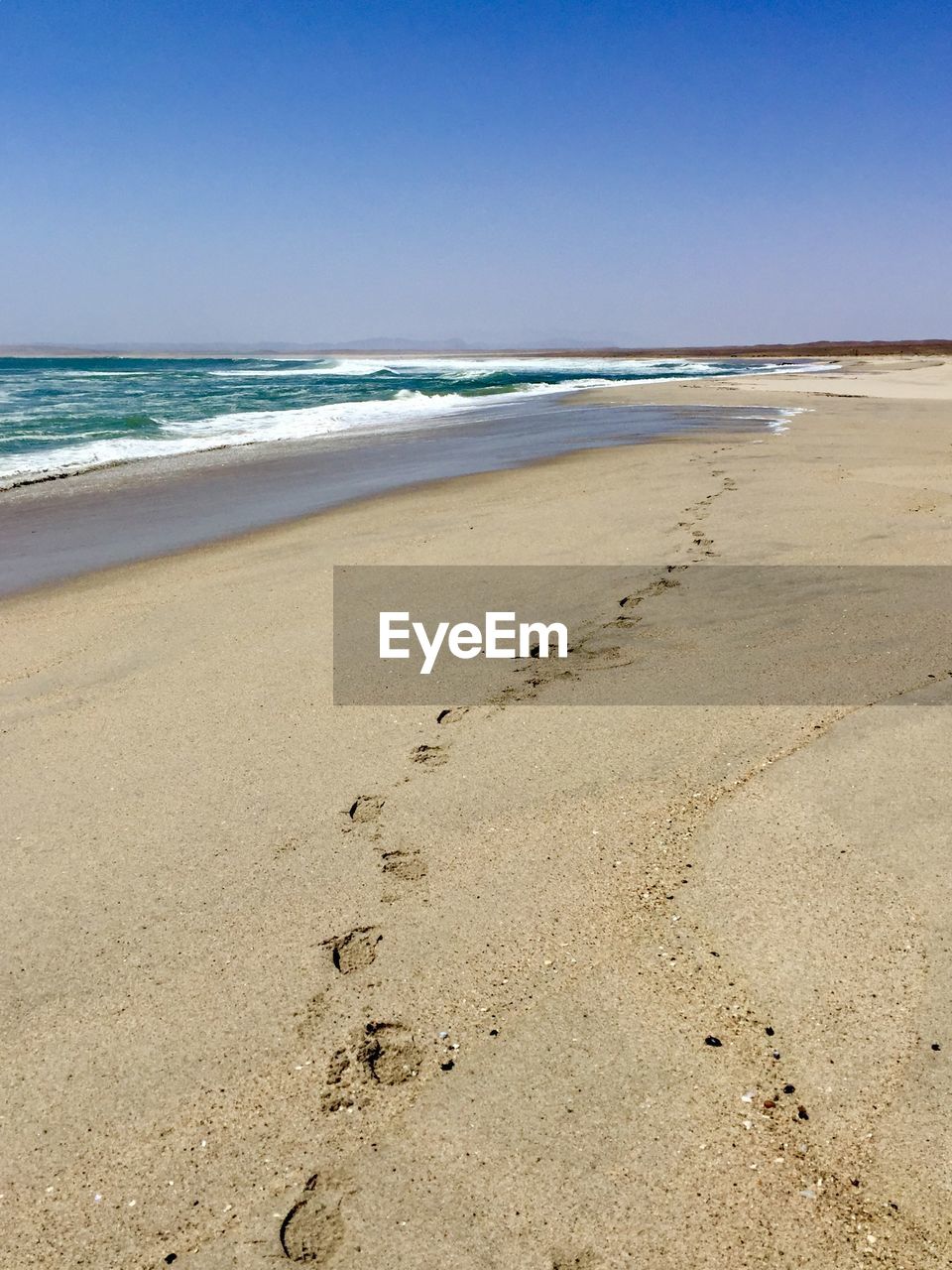 Scenic view of beach against clear blue sky